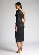 Back quarter image of a model wearing an black midi dress, featuring an asymmetric neckline with one long sleeve, with a side waist cut-out detail.The dress featured is the Vesper Niccola Black Satin Midi Dress