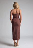 Back image of a blonde model wearing a Chocolate Midaxi Dress with a daring plunge neckline, delicate thin straps, a flattering bodycon fit and a faux wrap skirt split adds a touch of sophistication to the overall design. The design features the Vesper Oaklynn Chocolate Midaxi Dress