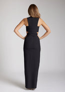 Back image of the model wearing a Black Cut-Out Maxi Dress with a round neckline and side waist cut-outs, and a front skirt split. The design features Vesper Paige Black Cut-Out Maxi Dress