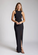 Front image of the model wearing a Black Cut-Out Maxi Dress with a round neckline and side waist cut-outs, and a front skirt split. The design features Vesper Paige Black Cut-Out Maxi Dress