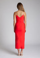 Back image of blonde model wearing a red midaxi dress with a plunge neckline, delicate thin straps for a feminine touch, and front split that adds a modern edge. The design featured is the Vesper Palmer Red Midaxi Dress 