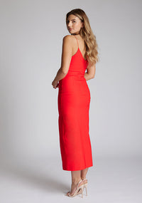 Back quarter image of blonde model wearing a red midaxi dress with a plunge neckline, delicate thin straps for a feminine touch, and front split that adds a modern edge. The design featured is the Vesper Palmer Red Midaxi Dress 