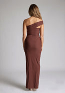 Back image of a blonde model wearing a  Chocolate Maxi Dress with an asymmetric neckline and one-sleeve design and front skirt split adds allure.The design features Vesper Pearson Chocolate Bardot Maxi Dress