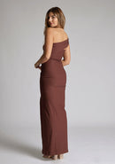Back quarter image of a blonde 
model wearing a  Chocolate Maxi Dress with an asymmetric neckline and one-sleeve design and front skirt split adds allure.The design features Vesper Pearson Chocolate Bardot Maxi Dress