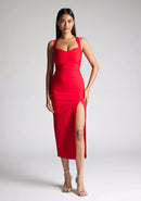 Front image of a  model wearing a red midaxi dress, featuring plunge sweetheart halter neck straps which cross at the back and a front skirt split. The dress featured is the Vesper Poppy Red Sweetheart Midaxi Dress