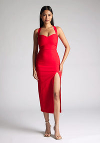 Front image of a  model wearing a red midaxi dress, featuring plunge sweetheart halter neck straps which cross at the back and a front skirt split. The dress featured is the Vesper Poppy Red Sweetheart Midaxi Dress