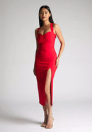 Front quarter image of a  model wearing a red midaxi dress, featuring plunge sweetheart halter neck straps which cross at the back and a front skirt split. The dress featured is the Vesper Poppy Red Sweetheart Midaxi Dress