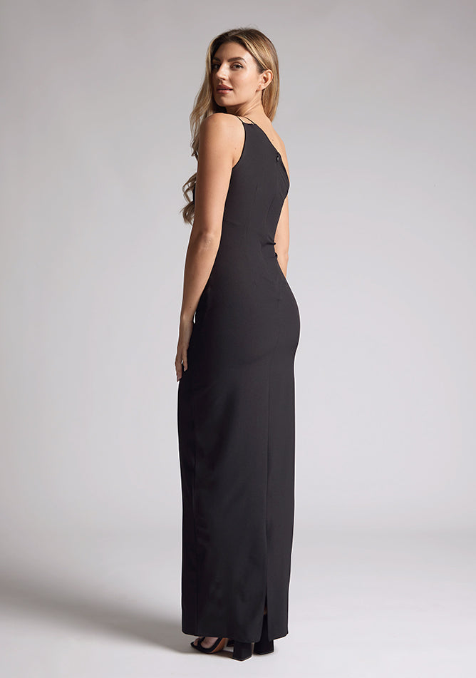 Back quarter image of the model wearing a black maxi dress with a one-shoulder dress, delicate thin strap, a chic front cutout and body con fit creating an effortlessly stylish look.  The design featured is the Vesper Rafaela Black Maxi Dress
