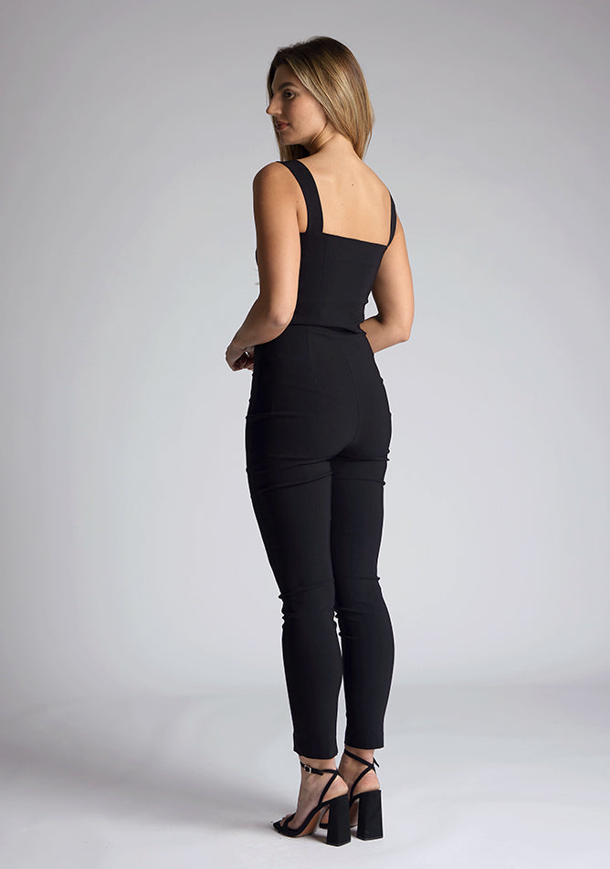 Back quarter image of a model wearing a black high waist trousers with a  high waist and fitted silhouette create a flattering shape, while the small splits at the front add a touch of elegance.The design featured is the Vesper Raven Black High Waist Trousers pair with Vesper Juno Black Crop Top