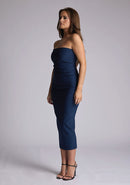 Front quarter image of a model wearing a navy midaxi dress, featuring a strapless neckline with gold zip at the back. The design featured is the Vesper Shelbie Navy Strapless Midaxi Dress