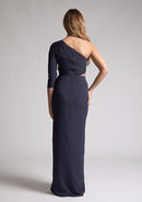 Back image of a blonde model wearing a  Navy Maxi Dress with an asymmetric long-sleeve design, coupled with a tasteful front cutout, creates a uniquely stylish statement. The design features is the Vesper Vienna Navy One Sleeve Maxi Dress