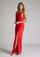 Front quarter image of a model wearing a red maxi dress with a asymmetric neckline, one shoulder strap, front skirt split and open back with asymmetric strap across back. The design featured is Vesper Viva Red Maxi Dress
