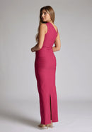 Back quarter image of a model wearing a raspberry asymmetric maxi dress with a asymmetric neckline silhouette, back skirt split and ruched detailing enhances the dress's allure. The design featured is the Vesper Wyatt Raspberry Asymmetric Maxi Dress