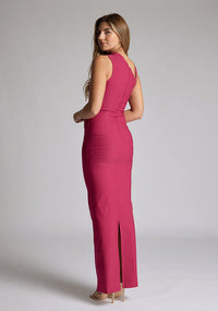 Back quarter image of a model wearing a raspberry asymmetric maxi dress with a asymmetric neckline silhouette, back skirt split and ruched detailing enhances the dress's allure. The design featured is the Vesper Wyatt Raspberry Asymmetric Maxi Dress